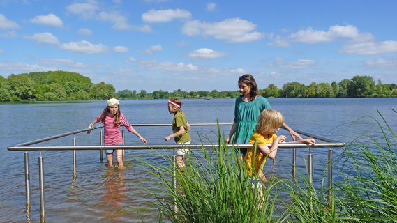Eine Familie probiert im sommerlichen Vörder See die Kneipp-Anlage aus