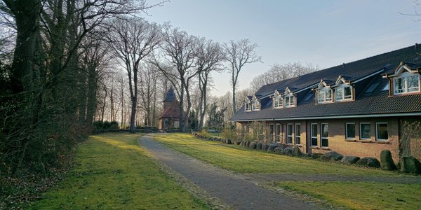 Der Weg neben der Freizeit- und Begegnungsstätte führt Richtung Kirche in Oese, die hinten klein zu sehen ist