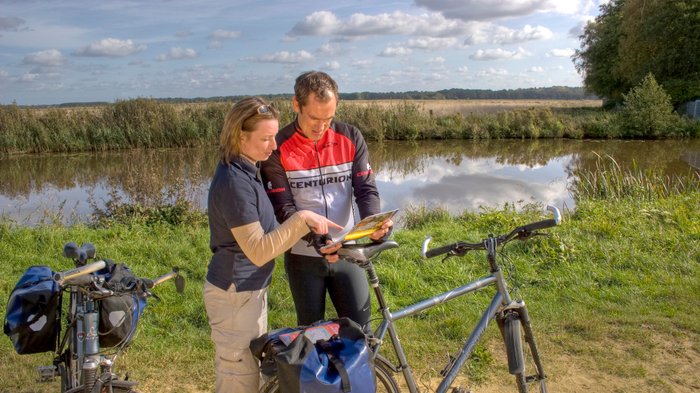 Zwei Radfahrer orientieren sich mit einer Karte in der Hand an der Wümme bei Ritterhude