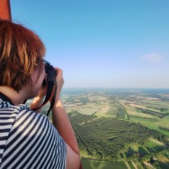 Ingrid fotografiert mit der Spiegelreflexkamera die Landschaft aus dem Ballon heraus