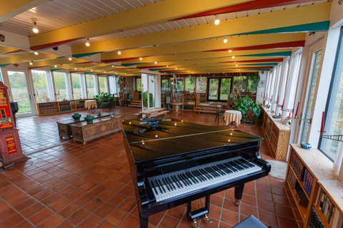 Im Vordergrund steht der große schwarze Flügel im Veranstaltungsraum von Haus Kreienhoop