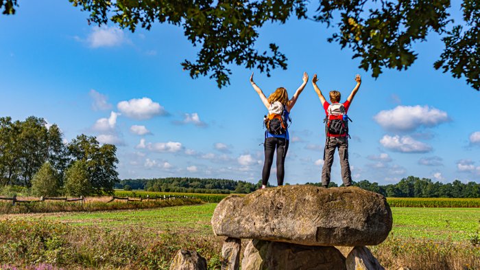 Zwei weibliche Wanderer stehen auf dem Großsteingrab Steinalkenheide und schauen in die Ferne