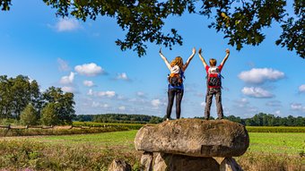 Zwei weibliche Wanderer stehen auf dem Großsteingrab Steinalkenheide und schauen in die Ferne