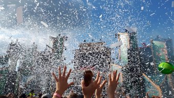 Besucher strecken die Hände hoch im Konfittiregen auf dem Elektropop-Festival Ferdinands Feld