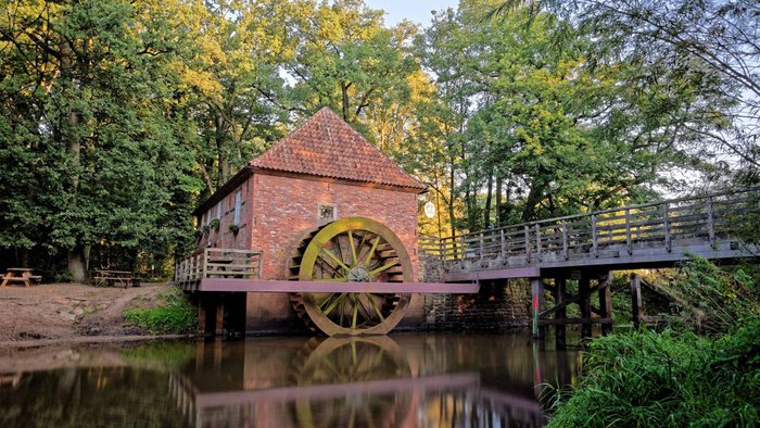 Blick auf die historische Wassermühle Eitzmühlen aus Backstein, davor der Fluss Oste