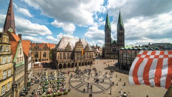 Blick von oben auf den Bremer Marktplatz mit dem UNESCO-Welterbe Rathaus, rechts ist die Bremer Speckflagge zu sehen