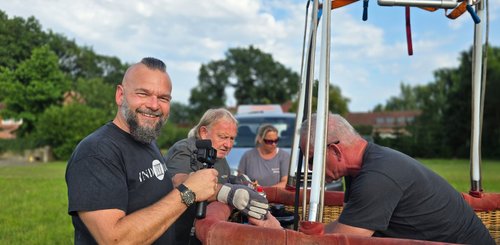 Der Filmemacher Ivica Ilievski steht mit seiner Kamera am Korb des Ballons und schaut in die Kamera, während das Team sich bespricht