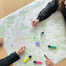 Drei Personen arbeiten mit bunten Stiften an einer Radkarte