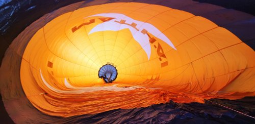 Miro ist ganz klein sichtbar, wie er im riesigen halb gefüllten orangefarbenen Heißluftballon arbeitet