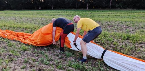 Miro und Udo rollen den Ballonstoff zusammen, und bücken sich dabei lustig nach vorne
