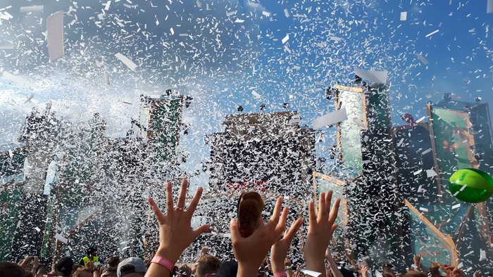 Besucher strecken die Hände hoch im Konfittiregen auf dem Elektropop-Festival Ferdinands Feld