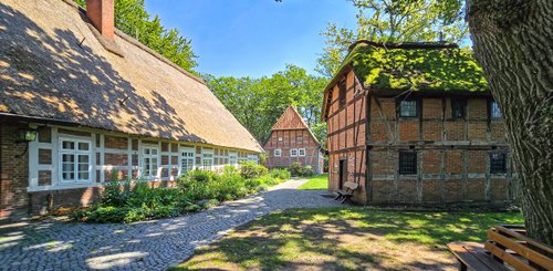 Eine malerische Ansammlung traditioneller Gebäude mit Reetdächern, die in einem ruhigen Garten stehen.