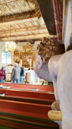 Ein Engel vom Epitaph ist in der Schärfe vor dem unscharfen Altarraum der Oeser Kirche zu sehen