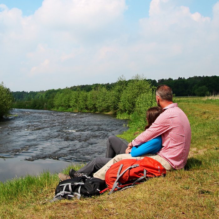 An einem Abschnitt der Wümme mit Stromschnelle kuschelt ein wanderndes Pärchen bei einer Pause