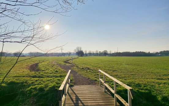 Blick in die weite Landschaft mit der Brücke, die auf den Kirchpfad Richtung Basdahl führt
