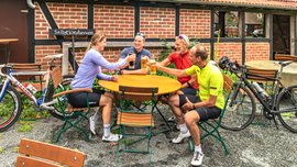 Rennradfahrer machen im Biergarten am Heimathaus eine Pause und stoßen an