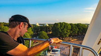 Eindruck von einem Riesenradfahrgast, der das lebhafte Treiben des Festivals unter ihm beobachtet, während der Tag endet.