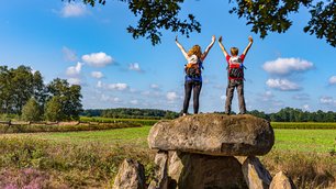 Zwei weibliche Wanderer stehen auf dem Großsteingrab Steinalkenheide und schauen in die Ferne