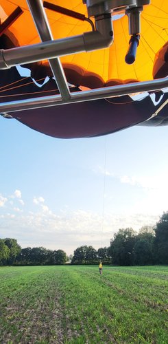 Udo steht klein im Hintergrund auf dem Landefeld und hält den Ballon am Seil, der oben im Bild zu sehen ist