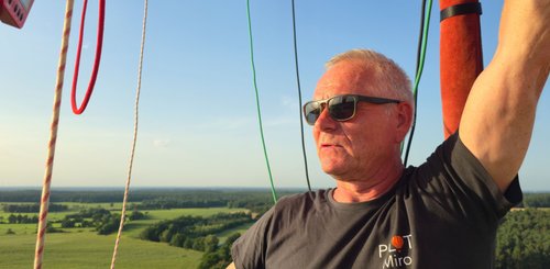 Miro navigiert mit seinem Arm den Heißluftballon, während er mit Sonnenbrille in die weite Landschaft schaut