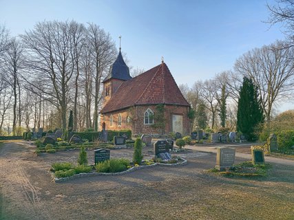 Kirche in Oese mit umlaufendem Friedhof, gesehen vom Tor