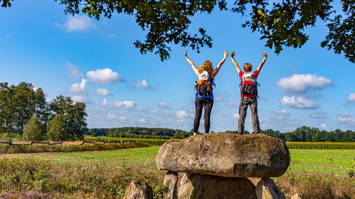 Zwei weibliche Wanderer stehen auf dem Großsteingrab Steinalkenheide und schauen in die Ferne