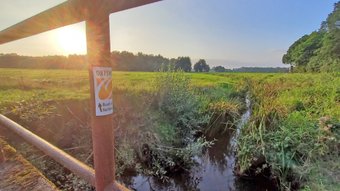Brücke am Visselbach mit dem Schild vom ORTSWEG Buchholz bei Sonnenuntergang
