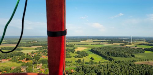 Blick vom Heißluftballon in die Landschaft, im Vordergrund ist ein rot ummantelter Stab des Ballons zu sehen