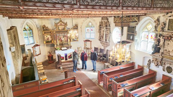 Blick von oben in den Altarraum der Oeser Kirche mit drei Personen bei einer Führung