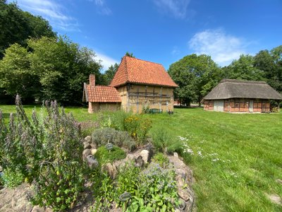 Kräuterspirale vor einem gelb getünchten Fachwerkhaus auf dem Heimathausgelände in Hesedorf