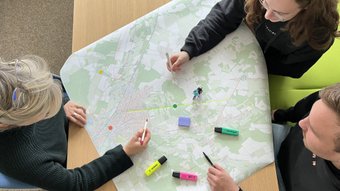 Drei Personen arbeiten mit bunten Stiften an einer Radkarte