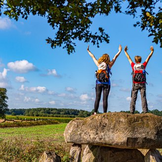 Zwei weibliche Wanderer stehen auf dem Großsteingrab Steinalkenheide und schauen in die Ferne