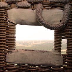 Blick durch ein Loch im Korb, das zum Einsteigen genutzt wird, in die weite Landschaft