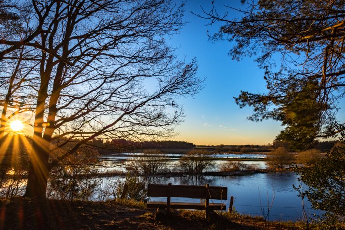 Eine Bank am Fluss Oste lädt zum Ausspannen und Genießen während des Sonnenuntergangs ein