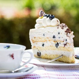 Eine Kaffeetasse und ein Stück Sahnetorte sind liebevoll angerichtet im Eichenhof-Café