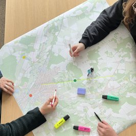 Drei Personen arbeiten mit bunten Stiften an einer Radkarte