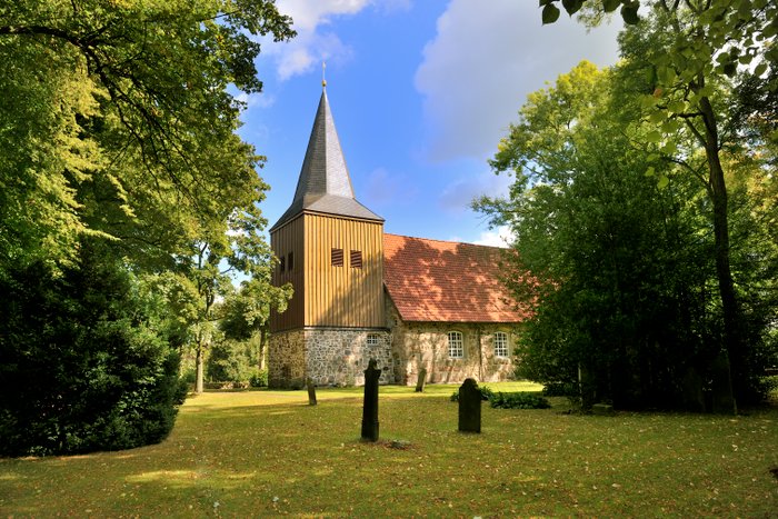Blick auf die historische Gangolf-Kirche in Oerel mit seinem prägnanten Kirchturm, der mit Holz verkleidet ist