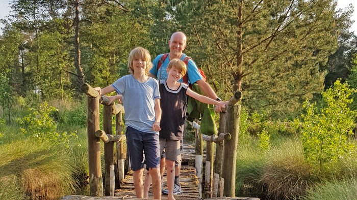 Eine Familie steht auf einer Brücke der Moorerlebniszone vom Tister Bauernmoor und schaut lachend in die Kamera