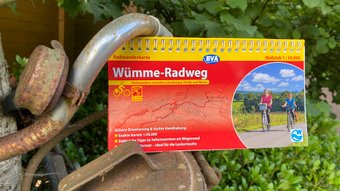 Eine Fahrradkarte vom Wümme-Radweg klemmt an einem verrosteten Deko-Fahrrad