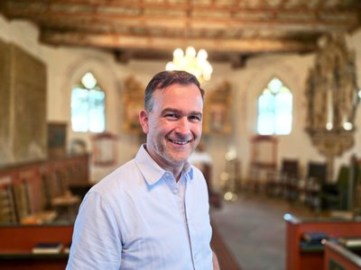 Portrait von Ralph Meyer in der Oeser Kirche vor dem unscharfen Altarraum