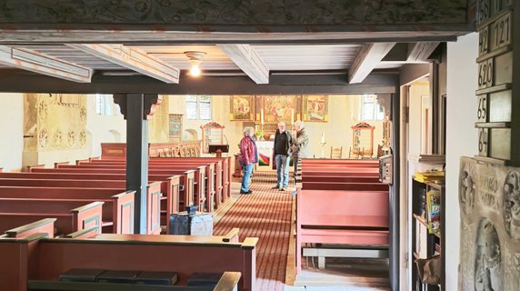 Unter der Orgel blickt man fast versteckt in die vordere Kirche mit drei sich unterhaltenden Personen