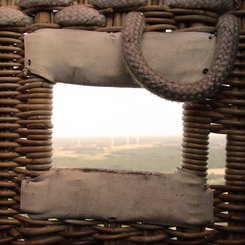 Blick durch ein Loch im Korb, das zum Einsteigen genutzt wird, in die weite Landschaft