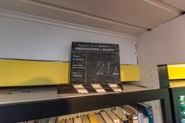 Auf einem Regal steht eine Tafel, wie sie beim Film verwendet wird, mit der Aufschrift des Films "Tadellöser und Wolff"