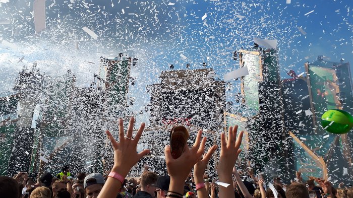 Besucher strecken die Hände hoch im Konfittiregen auf dem Elektropop-Festival Ferdinands Feld
