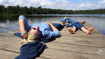 Eine Frau liegt mit ihren Kindern, alle blau gekleidet, entspannt auf dem Steg am Bullensee