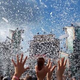 Besucher strecken die Hände hoch im Konfittiregen auf dem Elektropop-Festival Ferdinands Feld