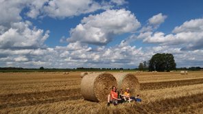 Eine Mutter sitzt auf einem Feld mit ihren beiden Söhnen vor zwei Strohballen