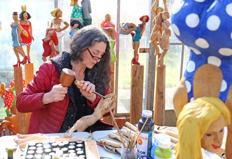 Zwischen bunten Holzskulpturen arbeitet die Künstlerin Ragna Reusch am nächsten Stück