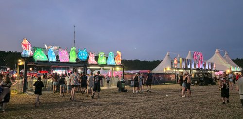 Bunte, beleuchtete Tierfiguren schmücken den Eingang eines Festivals, während fröhliche Besucher auf den Platz strömen.