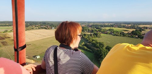 Ingrid schaut vom Heißluftballon aus in die weite flache Landschaft